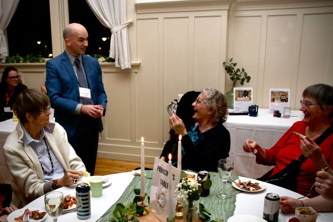 A spectator holds her selected playing card in surprise during a close-up magic performance