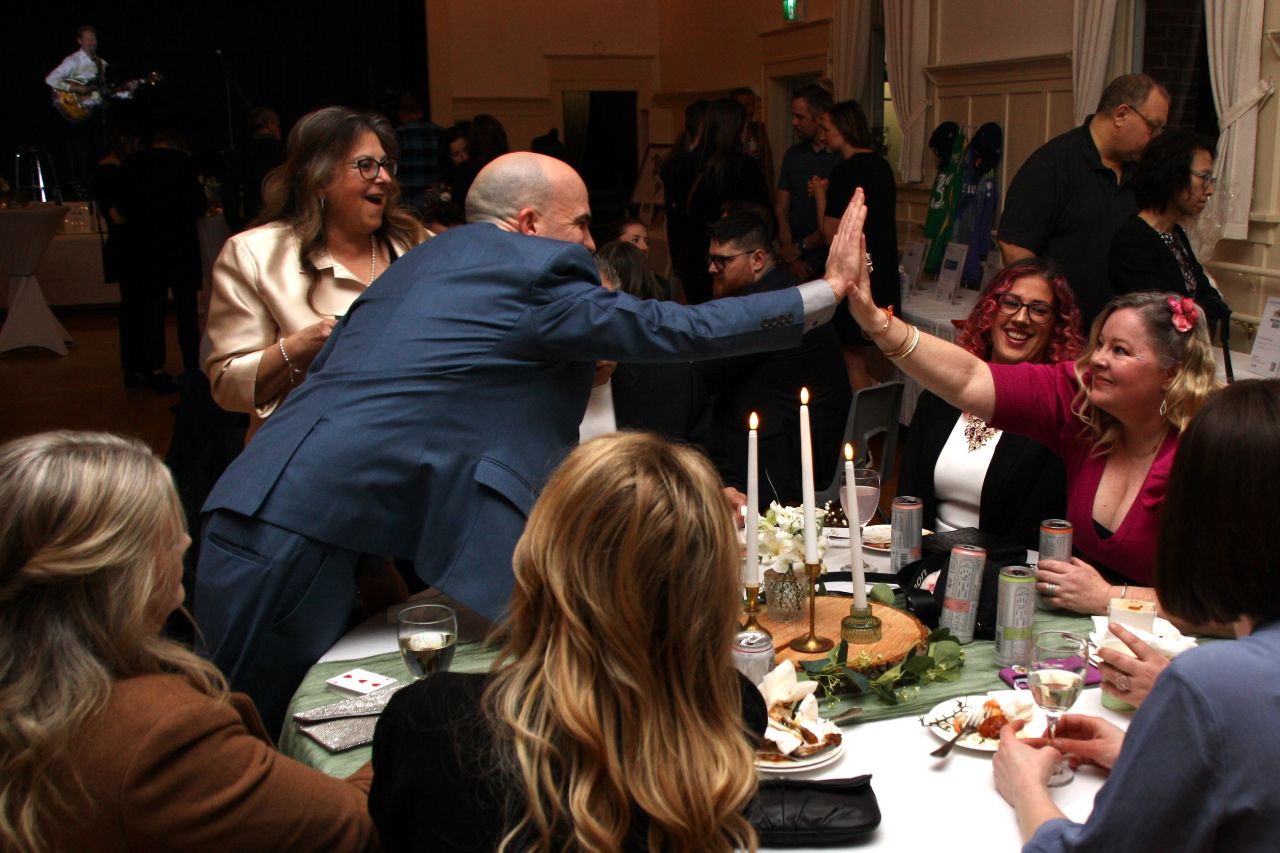 Geo and a guest share a high-five across the table after a moment of close-up magic